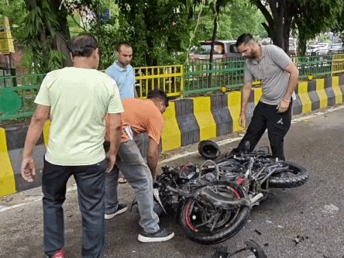 बाइक को रास्ते से हटाकर साइड करते लोग।