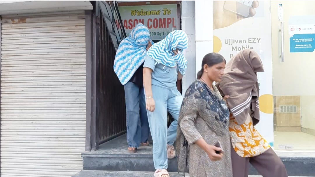युवतियों को होटल से बाहर लेकर आते हुए महिला पुलिस। अपना मुंह छिपाए हुए युवतियां