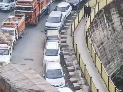 ढली सब्जी और पुलिस स्टेशन के बीच सड़क किनारे पार्क गाड़ियां और सड़क पर लगा ट्रैफिक जाम।