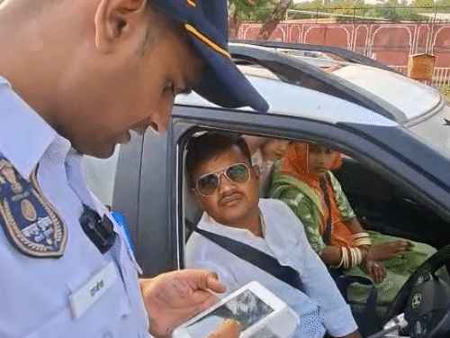 गाड़ी ड्राइवर महेंद्र सिंह को पॉल्यूशन पेंडिंग के बारे में बताते ट्रैफिक पुलिसकर्मी।