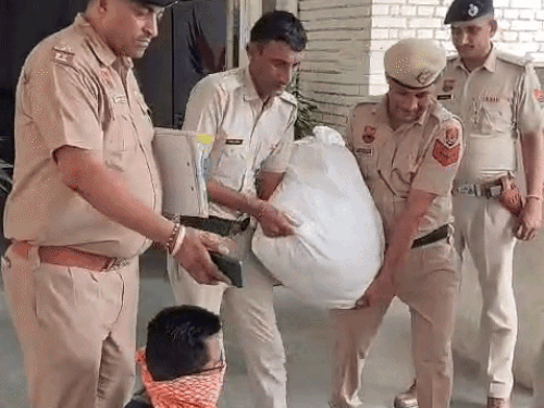 अफीम को कट्‌टे में भरकर लाते हुए पुलिसकर्मी और नीचे बैठा मुंह पर कपड़ा बांधे ट्रक ड्राइवर