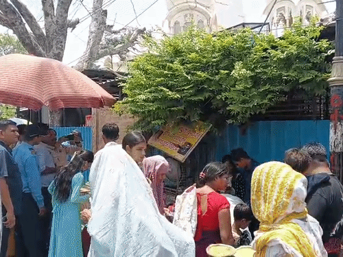 इस्कॉन मंदिर के बाहर लगे कूलर की हवा लेते श्रद्धालु।