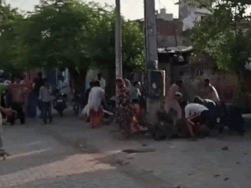 सड़क किनारे पड़े ईंट-पत्थर उठाकर पुलिस कर्मियों पर फेंकते लोग।