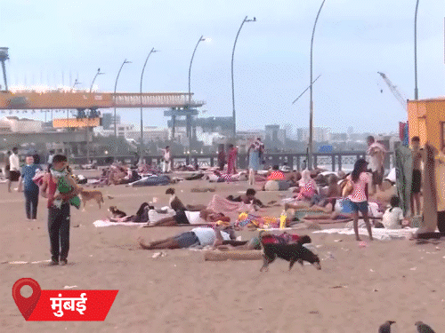 मुंबई में गर्मी से राहत के लिए बीच पर सोते लोग।