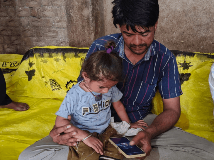 मुकेश पास में बैठे अपने दो साल के बेटे मितांश को मोबाइल पर अपनी मां की तस्वीरें दिखा रहा था।