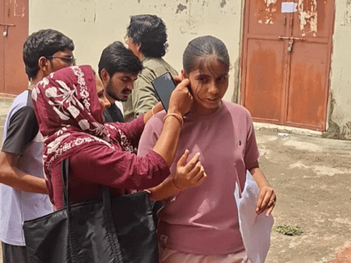 परीक्षा केंद्र में प्रवेश से पहले युवती के परिजन गले की चेन और कान की बालियां उतारते हुए।