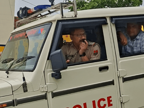 परीक्षा केंद्र के बाहर से लोगों को अनाउंसमेंट करके हटवाते हुए पुलिस।