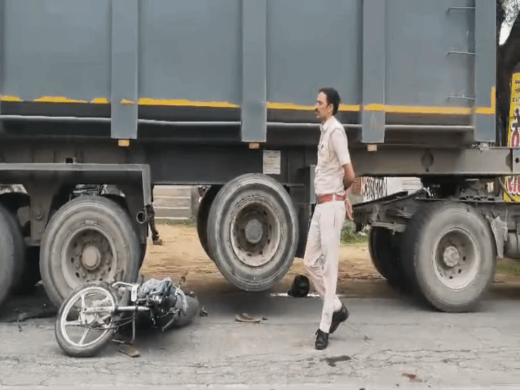 डंपर की टक्कर के बाद पहियों के नीचे फंसी बाइक।