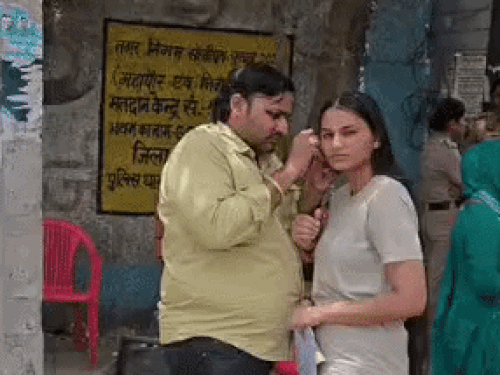 एग्जाम सेंटर के बाहर कान की बाली निकालते हुए अभिभावक।
