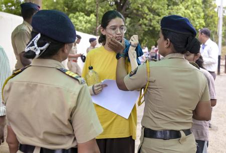 महाराष्ट्र के नागपुर में एक परीक्षा केंद्र पर उम्मीदवार की सुरक्षा जांच करते पुलिसकर्मी।