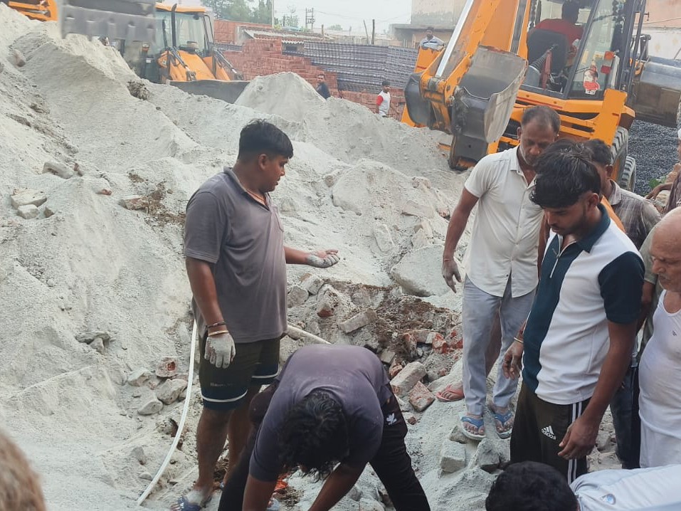फरीदाबाद में दीवार गिरने के बाद मलबा हटाते लोग।