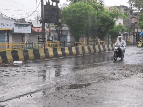 जालंधर में बारिश के बीच रेनकोट पहनकर बाइक चलाता युवक