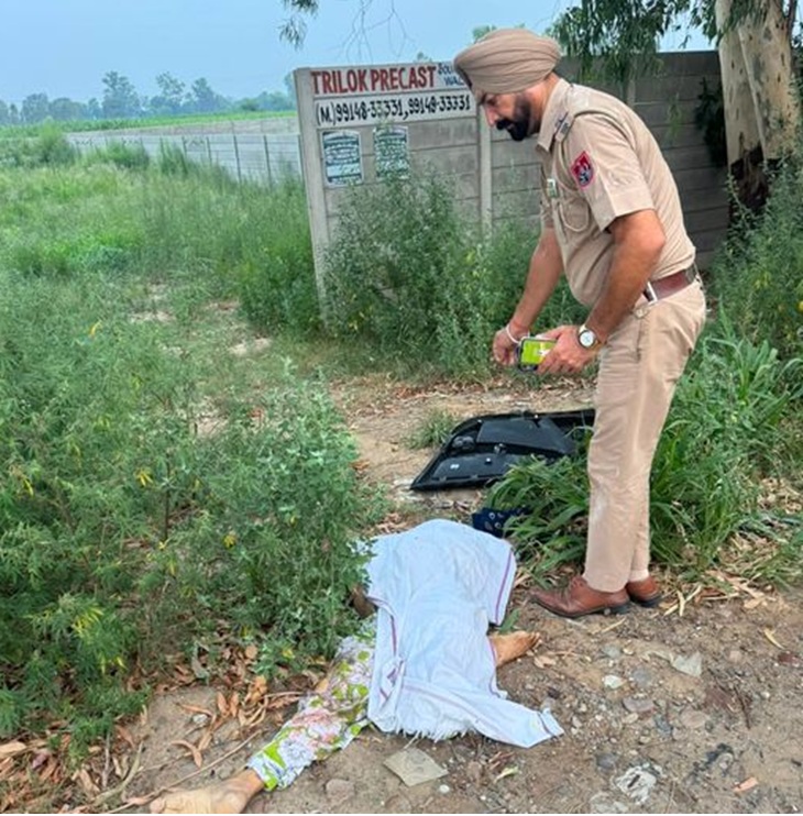 सड़क किनारे पड़ी महिला की लाश और जांच के लिए पहुंचे पुलिस कर्मचारी।