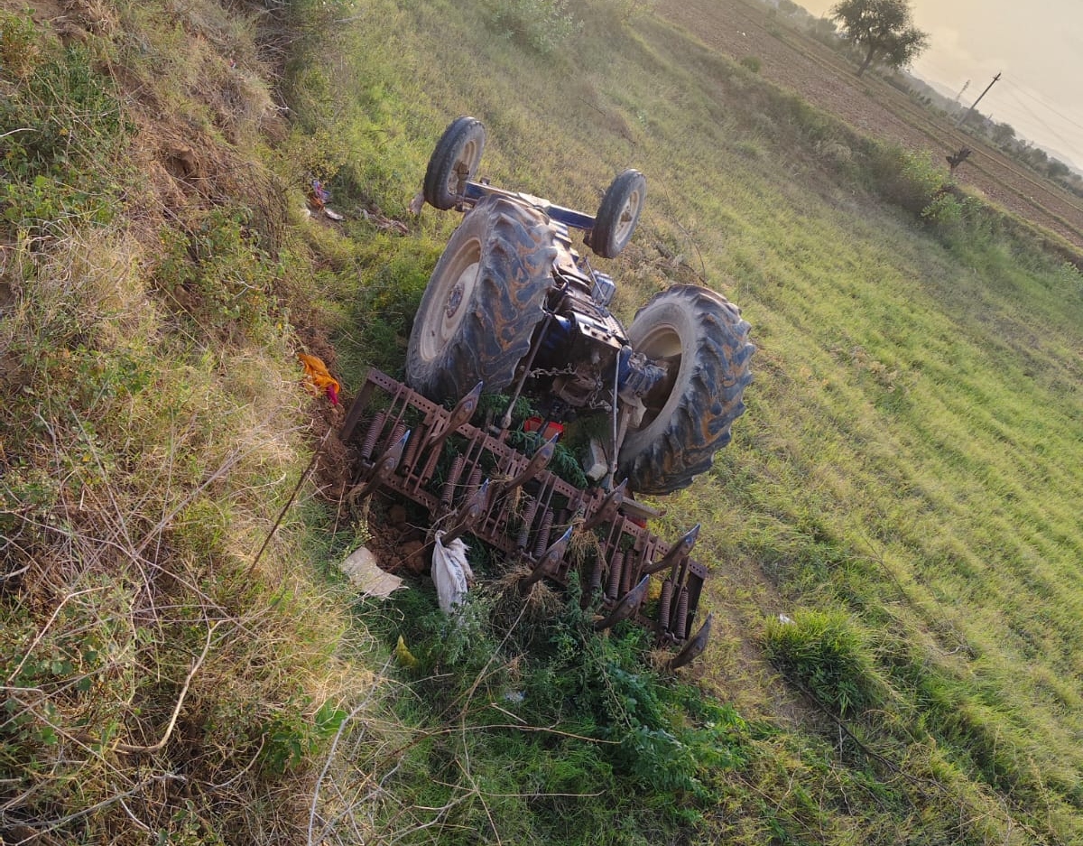 खेत में पलटा ट्रैक्टर।