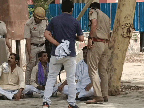 जमीन पर बैठे कांग्रेस के शहरी जिला अध्यक्ष प्रदीप गुलिया व अन्य को उठाते पुलिस अधिकारी।