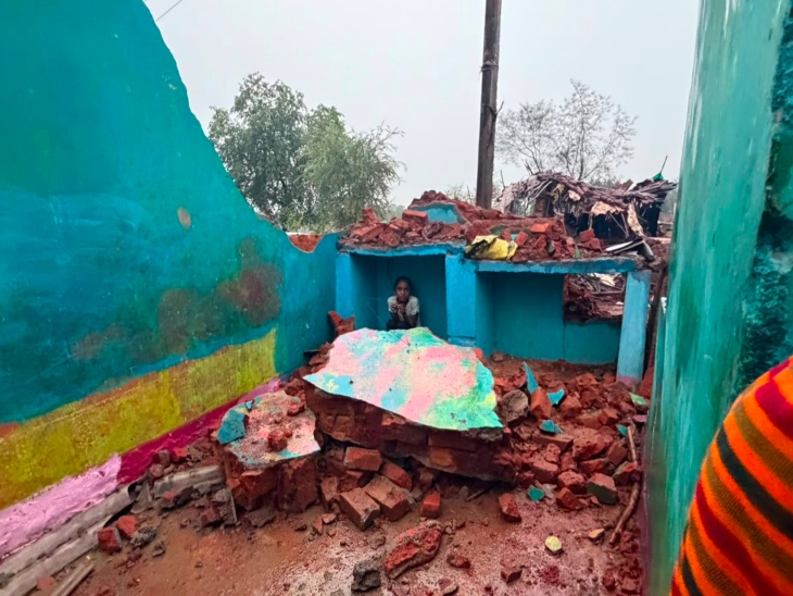 बारिश के बीच टूटे-फूटे घर में बैठी मासूम बच्ची।