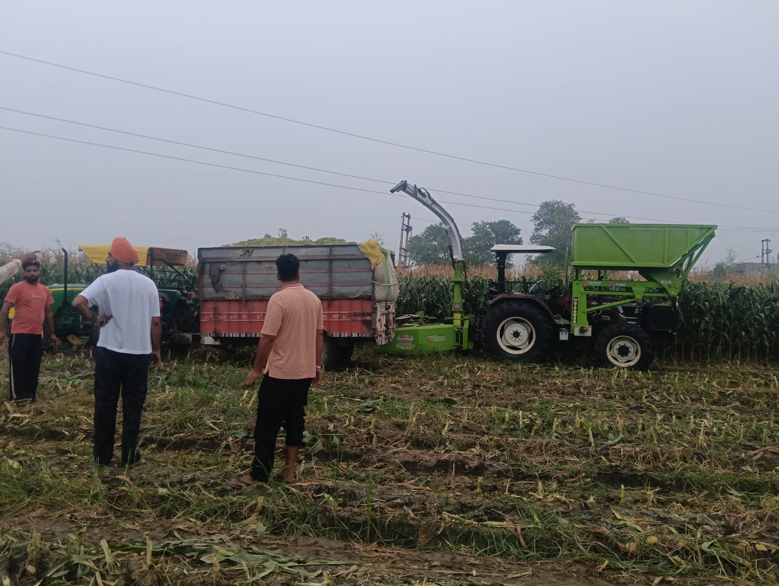 बुर्जकर्मगढ में हादसे के बाद मौके पर पहुंचे परिजन और खड़ी मशीन व ट्रैक्टर-ट्राली। ऊपर से गुजर रही बिजली की तारें