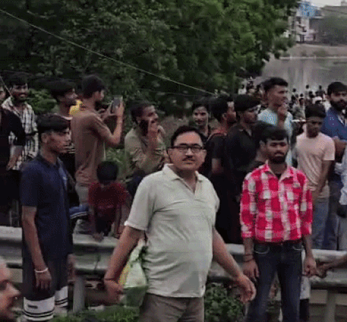 युवक के टावर पर चढ़ने के बाद उसे देखने के लिए जमा हुए लोग।