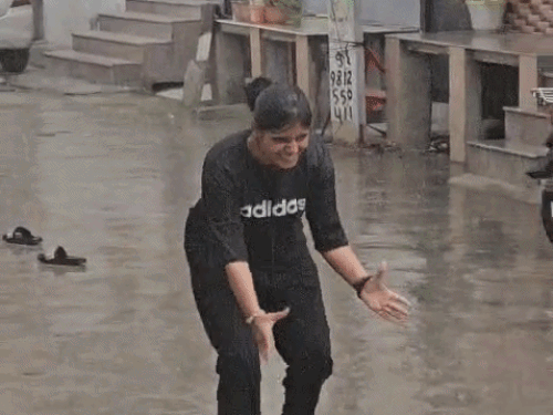 झज्जर में तेज बारिश के बाद महिला बच्चों के साथ बारिश में भीगती हुई।