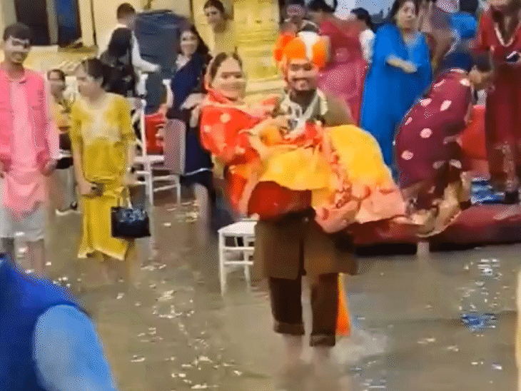 इंदौर में लगातार बारिश के बीच कैट रोड स्थित एक मैरिज गार्डन में पानी भर गया। इस बीच दूल्हा-दुल्हन ने पूरे उत्साह से सभी रस्में निभाईं। पानी से भरे रास्ते के कारण दूल्हे वैभव ने दुल्हन पूर्वा को गोद में उठाकर मंडप से हॉल तक पहुंचाया।