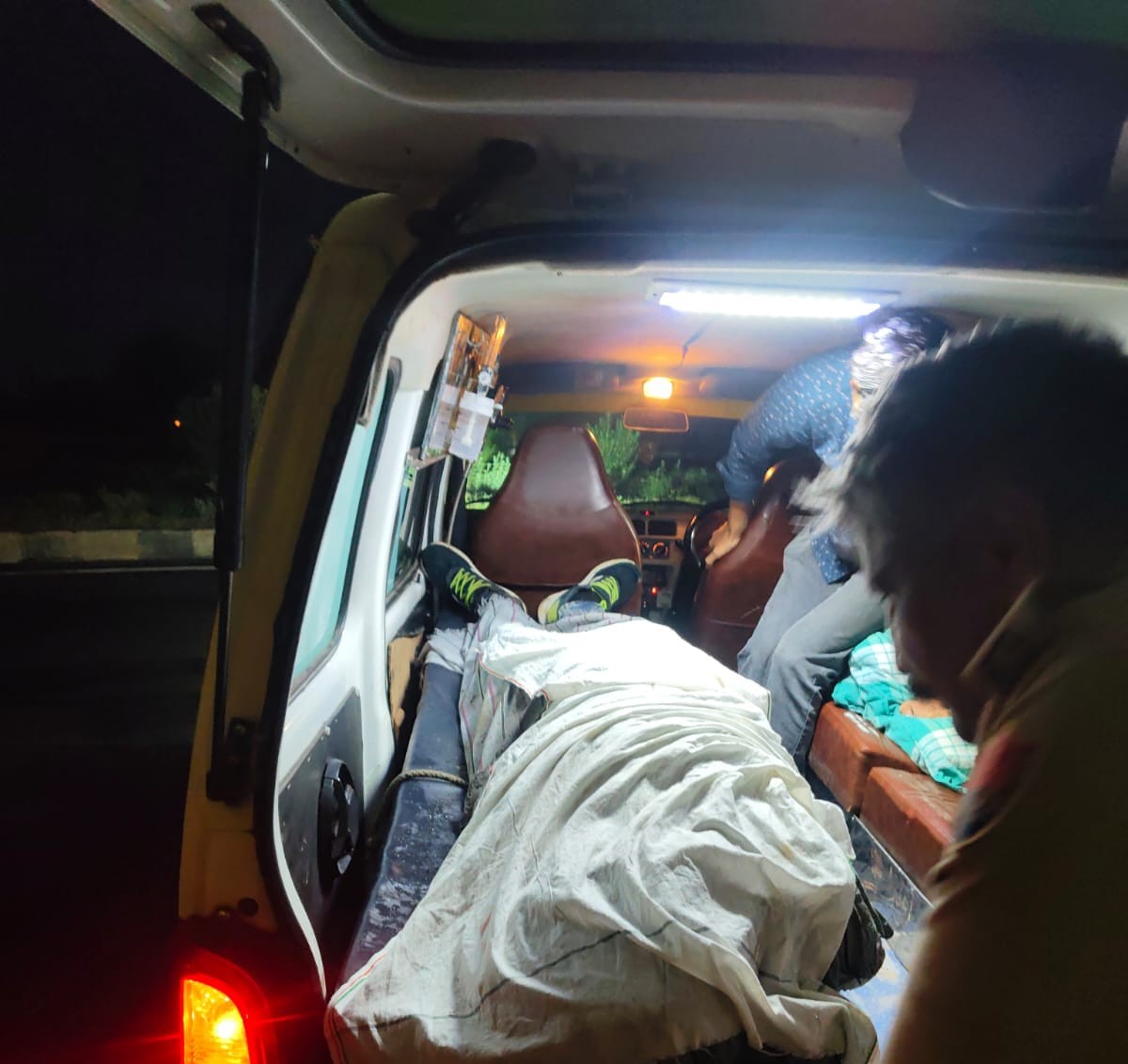 ट्रक के नीचे फंसने मृत पुलिस जवान के शव को अस्पताल ले जाते पुलिसकर्मी।