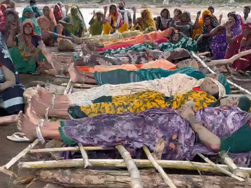 विरोध प्रदर्शन के तहत महिलाएं लकड़ी पर लेटी हुई हैं।