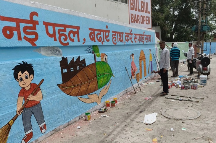 जींद में रानी तालाब के पास दीवारों पर पेंट करते पेंटर।