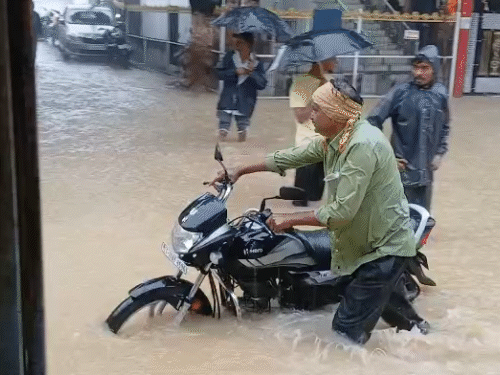 सड़कों पर इतना पानी भर गया कि लोगों को बाइक धकेलकर निकलना पड़ रहा है।