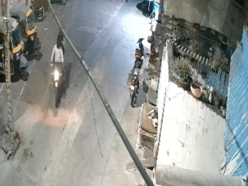 तीन बाइक सवार बदमाशों में से एक बदमाश बाइक से उतरता है।
