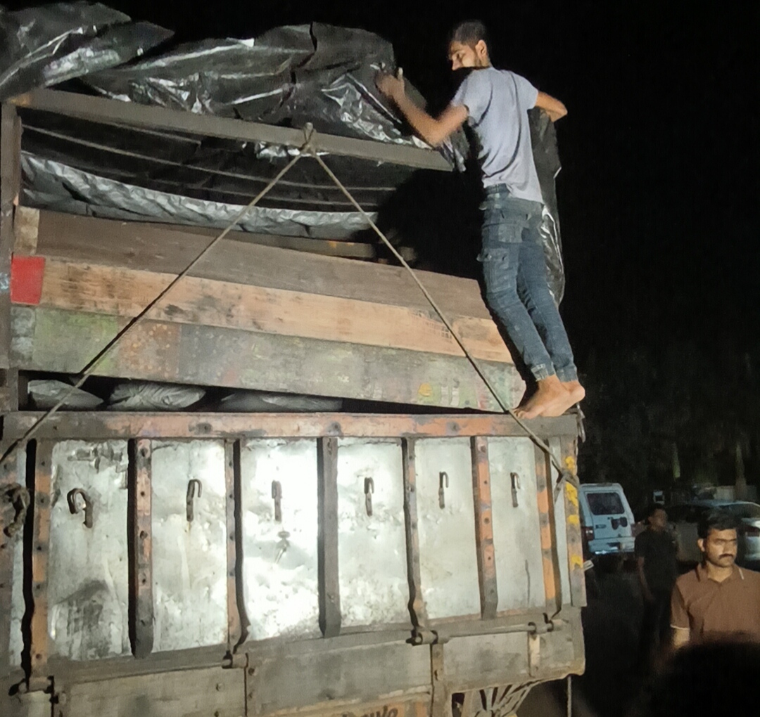 चालक ट्रक का तिरपाल हटाकर ट्रॉली खोल रहा है।