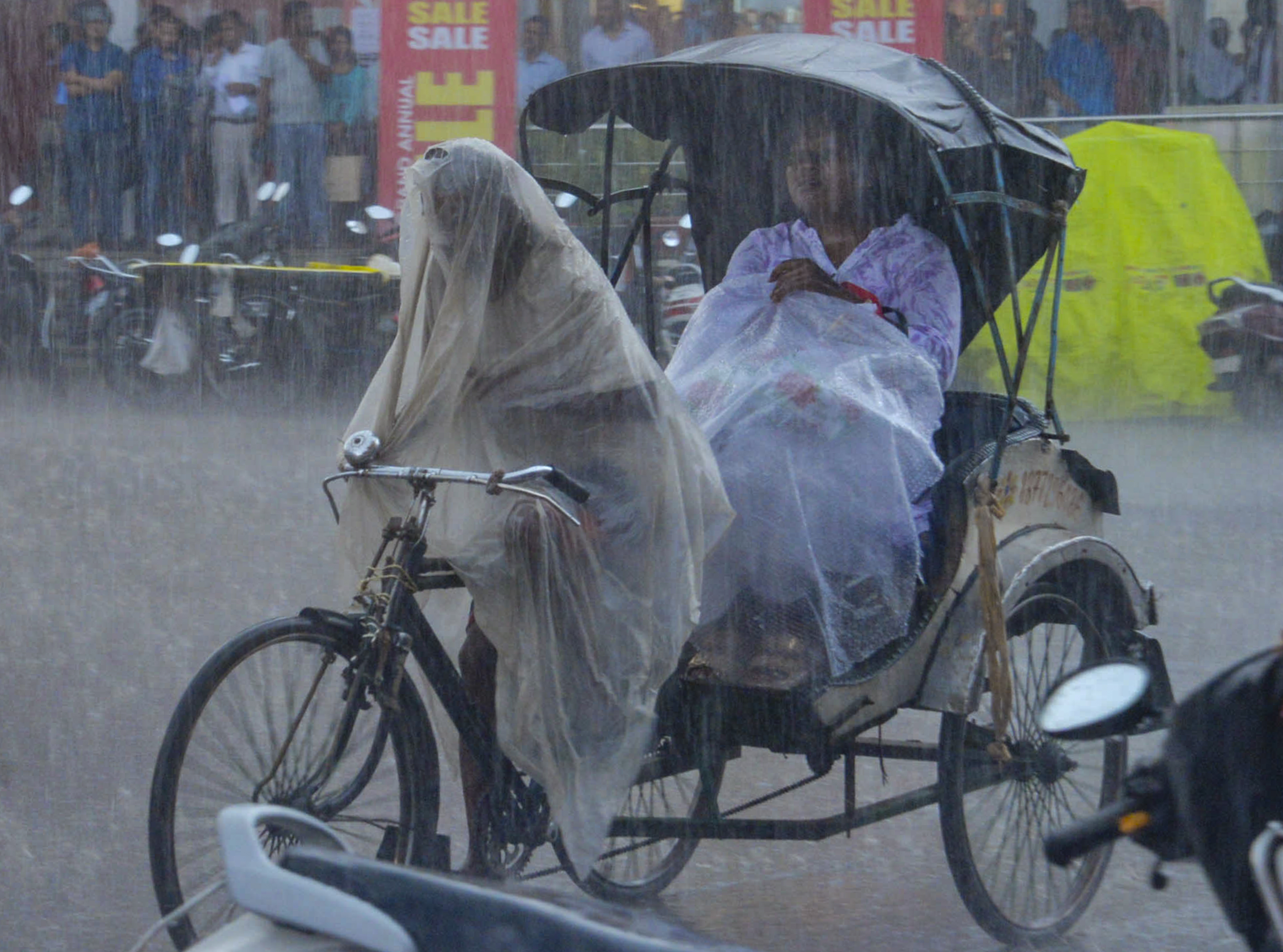 Heavy rain occurred in Ranchi, Jharkhand on Saturday. Meanwhile, a rickshaw driver and the passenger sitting in it were seen covering themselves with a plastic sheet.