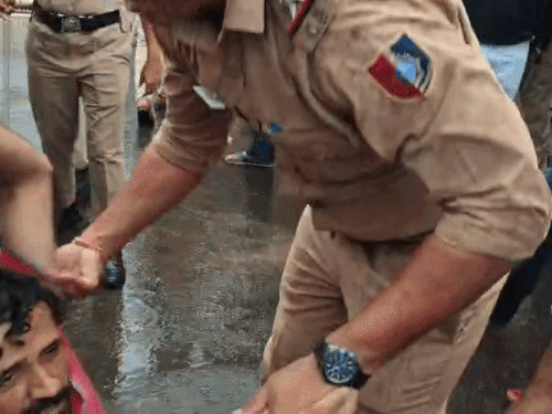 पुलिस ने प्रदर्शन कर रहे छात्र को उठाया और गाड़ी में बैठा लिया।