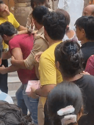 महिला सिपाही लाल टी-शर्ट पहने युवक को मार रही है। एक सिपाही उसे पकड़े हुए है।