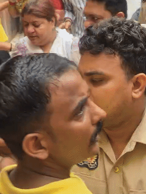 लाल टी-शर्ट वाले युवक को महिला सिपाही और उसके साथी मंदिर से धकियाते हुए बाहर लेकर जाते हुए।