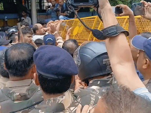 बैरिकेडिंग के ऊपर चढ़ने की कोशिश करते हुए छात्रा।