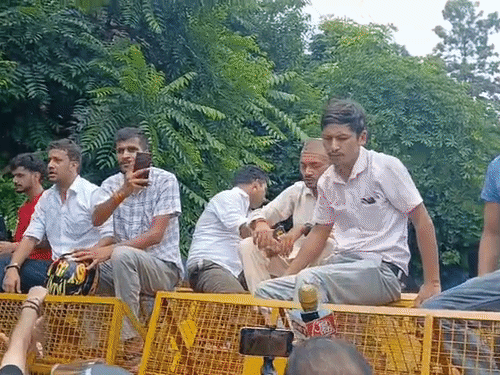 बैरिकेडिंग के ऊपर चढ़े छात्रा और प्रदर्शनकारी