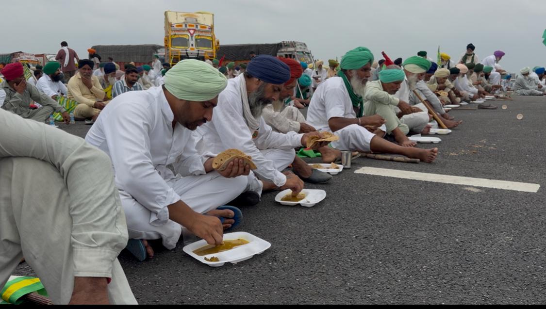 कैथल में दिल्ली-जम्मू कटरा एक्सप्रेस-वे पर बैठकर खाना खाते किसान।