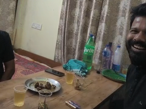 टेबल पर शराब, चिकन और सिगरेट का डिब्बा दिखाई दे रहा है।