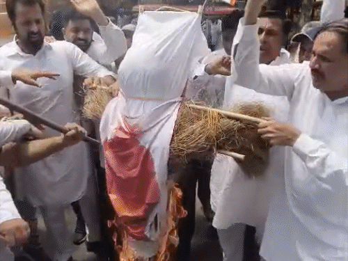 पीएम मोदी के पुतले को लाठी मारकर आगे हवाले करते कांग्रेस नेता।