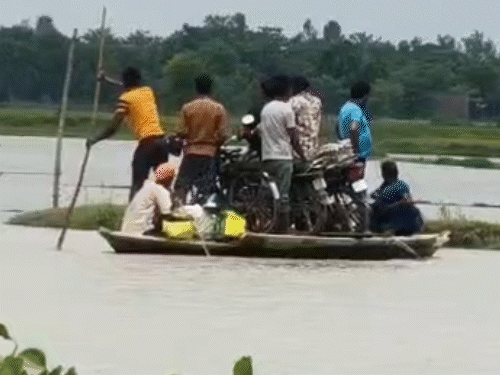 In Sitapur, UP, river water has entered the villages. In one village, water is flowing over a dirt road. Villagers are commuting by boat.