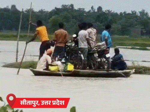 यूपी के सीतापुर में सड़क पर पानी भर गया। गांव के लोग नाव में बैठकर जा रहे हैं।