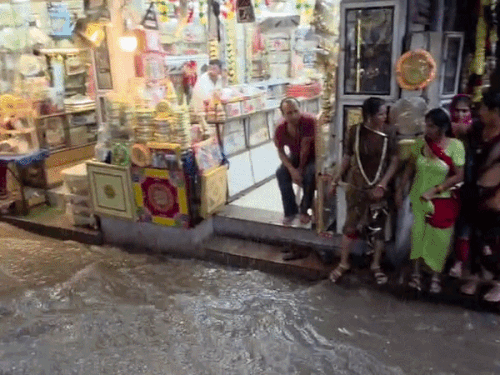 फोटो शहर के त्रिपोलिया का है। यहां बारिश से बचने के लिए महिलाओं को दुकान का सहारा लेना पड़ा।