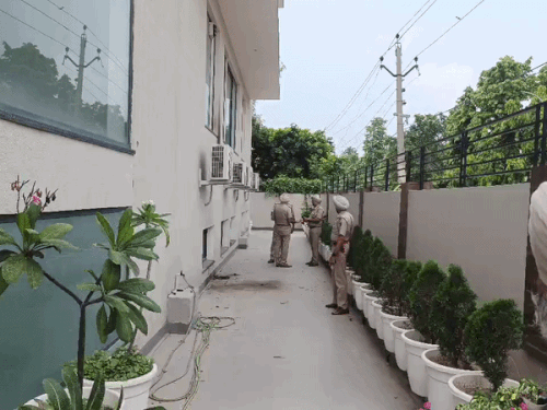पेट्रोल बम हमले के बाद दीवार के पास जांच करती पुलिस।