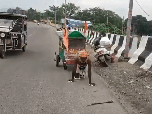 घुटनों के बल चलकर कांवड़ ले जाता व्यक्ति।