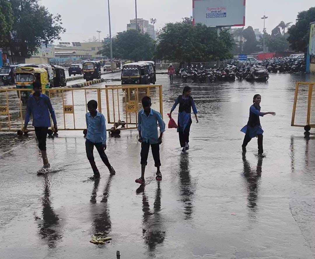 रेलवे स्टेशन पर बारिश में भीगते बच्चे।
