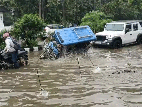 मॉडल टाउन में बारिश के पानी में पलटता ई-रिक्शा।