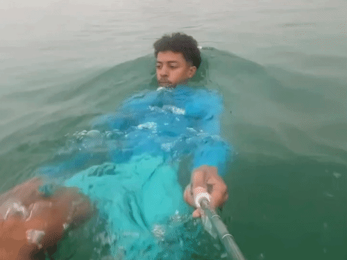 मोरक्को का एक प्रवासी सेल्फी स्टिक से वीडियो बनाते हुए समुद्र तैरकर स्पेन के स्यूटा शहर में दाखिल होता हुआ।