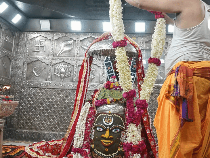 भगवान महाकाल को फूलों की माला पहनाते पुजारी।