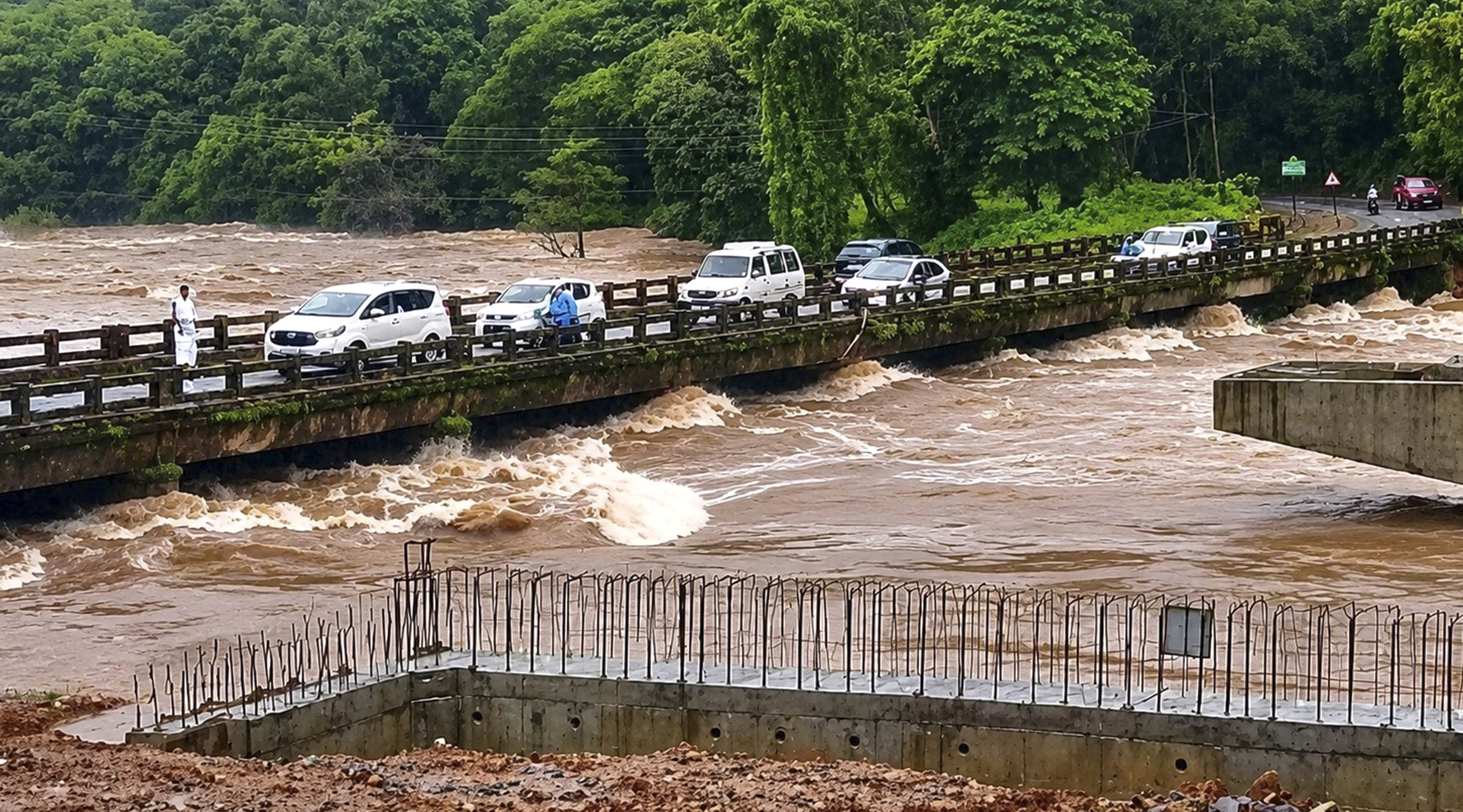 Vehicles are passing over the bridge built above the overflowing Netravati river amidst heavy rains.