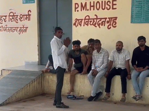 Villagers sitting outside the post-mortem room.